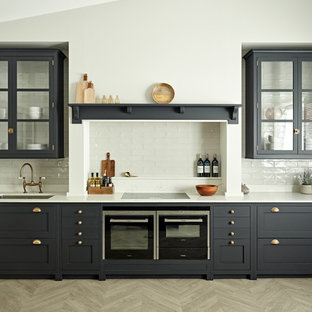 Design ideas for a victorian single-wall eat-in kitchen in Surrey with an undermount sink, shaker cabinets, blue cabinets, solid surface benchtops, white splashback, subway tile splashback, black appliances, light hardwood floors, beige floor and white benchtop.