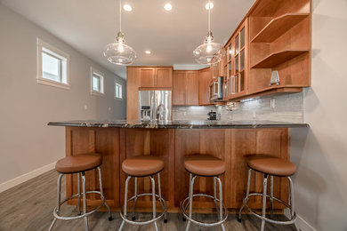 Example of a mid-sized trendy u-shaped vinyl floor and gray floor open concept kitchen design in Vancouver with an undermount sink, shaker cabinets, medium tone wood cabinets, granite countertops, white backsplash, glass tile backsplash, stainless steel appliances, an island and black countertops