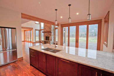 Example of a large arts and crafts galley dark wood floor and brown floor eat-in kitchen design in Vancouver with a double-bowl sink, dark wood cabinets, stainless steel appliances, an island, shaker cabinets and quartz countertops