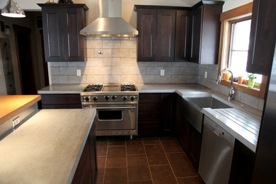 Ejemplo de cocina clásica renovada con puertas de armario marrones, encimera de cemento, salpicadero verde y electrodomésticos de acero inoxidable