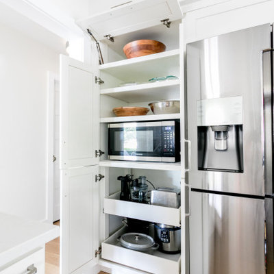 Example of a mid-sized transitional u-shaped light wood floor and brown floor kitchen design in Austin with an undermount sink, shaker cabinets, white cabinets, quartz countertops, white backsplash, ceramic backsplash, stainless steel appliances, a peninsula and white countertops