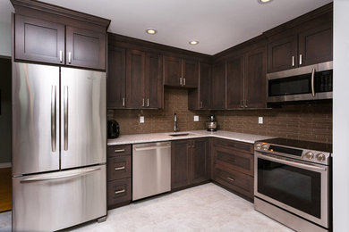 Inspiration for a mid-sized timeless u-shaped kitchen remodel in Calgary with an undermount sink, shaker cabinets, dark wood cabinets, stainless steel appliances, brown backsplash, mosaic tile backsplash and no island