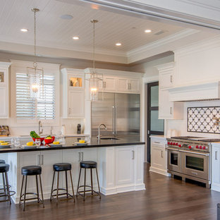 Traditional enclosed kitchen inspiration - Example of a classic l-shaped dark wood floor enclosed kitchen design in Los Angeles with shaker cabinets, white cabinets, white backsplash, stainless steel appliances and an island