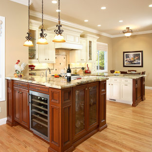 Foto di una cucina ad U classica di medie dimensioni con top in granito, lavello sottopiano, ante con riquadro incassato, paraspruzzi beige, elettrodomestici in acciaio inossidabile, parquet chiaro, ante in legno scuro, penisola e paraspruzzi in pietra calcarea