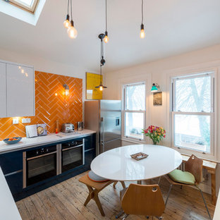 Inspiration for a medium sized eclectic u-shaped kitchen/diner in London with a submerged sink, flat-panel cabinets, black cabinets, orange splashback, metro tiled splashback, stainless steel appliances, medium hardwood flooring, no island, brown floors and white worktops.