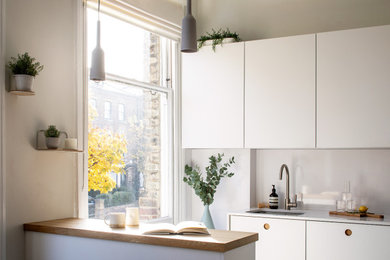 This is an example of a small modern l-shaped kitchen in London with a submerged sink, flat-panel cabinets, quartz worktops, white splashback, engineered quartz splashback, integrated appliances, ceramic flooring, a breakfast bar, grey floors and white worktops.
