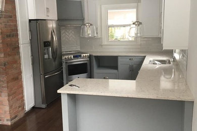 Example of a small transitional u-shaped medium tone wood floor and brown floor eat-in kitchen design in Toronto with an undermount sink, shaker cabinets, gray cabinets, quartz countertops, white backsplash, subway tile backsplash, stainless steel appliances and a peninsula