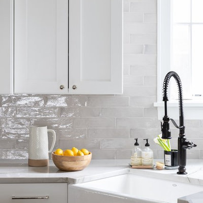 Example of a large farmhouse u-shaped light wood floor and beige floor enclosed kitchen design in Chicago with a farmhouse sink, shaker cabinets, white cabinets, marble countertops, gray backsplash, ceramic backsplash, stainless steel appliances, an island and white countertops