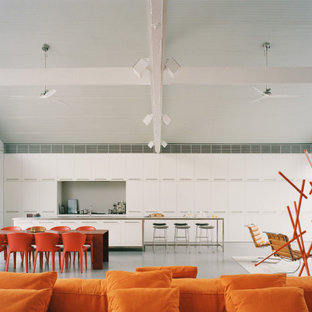 Industrial galley open plan kitchen in Sydney with flat-panel cabinets, white cabinets, concrete floors, with island, grey floor, grey benchtop and vaulted.