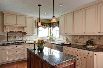 Mid-sized transitional l-shaped medium tone wood floor eat-in kitchen photo in Other with an undermount sink, raised-panel cabinets, beige cabinets, granite countertops, beige backsplash, ceramic backsplash, stainless steel appliances and an island