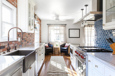 Example of a mid-sized farmhouse galley medium tone wood floor and brown floor eat-in kitchen design in Sacramento with a farmhouse sink, shaker cabinets, white cabinets, quartzite countertops, blue backsplash, ceramic backsplash, stainless steel appliances and an island