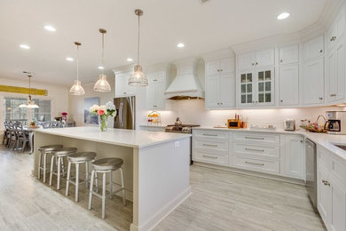 Inspiration for a large transitional light wood floor and beige floor eat-in kitchen remodel in Birmingham with a farmhouse sink, shaker cabinets, white cabinets, quartz countertops, white backsplash, subway tile backsplash, stainless steel appliances and an island