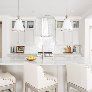 Mid-sized transitional kitchen ideas - Inspiration for a mid-sized transitional galley kitchen remodel in Charlotte with an undermount sink, shaker cabinets, beige cabinets, white backsplash, stainless steel appliances, an island and white countertops
