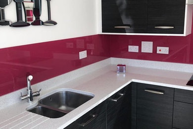 Imagen de cocina minimalista de tamaño medio con salpicadero rosa y salpicadero de vidrio templado