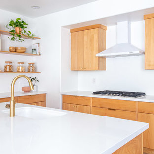 Inspiration for a mid-sized midcentury u-shaped eat-in kitchen in Phoenix with an undermount sink, flat-panel cabinets, light wood cabinets, quartz benchtops, white splashback, stainless steel appliances, light hardwood floors, with island, brown floor and white benchtop.