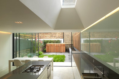 Foto di una cucina design di medie dimensioni con lavello a doppia vasca, ante lisce, ante bianche, paraspruzzi grigio, elettrodomestici in acciaio inossidabile e pavimento in cemento