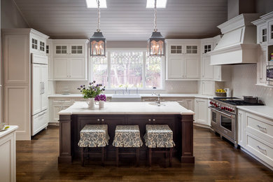 Farmhouse u-shaped dark wood floor enclosed kitchen photo in San Francisco with a farmhouse sink, beaded inset cabinets, white cabinets, white backsplash, an island and paneled appliances