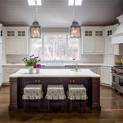 Farmhouse u-shaped dark wood floor enclosed kitchen photo in San Francisco with a farmhouse sink, beaded inset cabinets, white cabinets, white backsplash, an island and paneled appliances