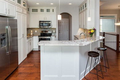 Mid-sized transitional u-shaped medium tone wood floor eat-in kitchen photo in Other with an undermount sink, shaker cabinets, white cabinets, granite countertops, gray backsplash, glass tile backsplash, stainless steel appliances and a peninsula