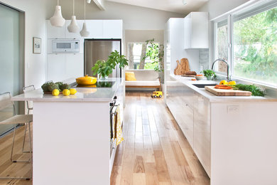 Kitchen - mid-sized contemporary light wood floor kitchen idea in Vancouver with a single-bowl sink, flat-panel cabinets, white cabinets, quartz countertops, gray backsplash, glass tile backsplash, stainless steel appliances and an island
