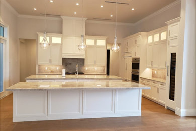 Large minimalist u-shaped light wood floor and brown floor open concept kitchen photo in Miami with a single-bowl sink, recessed-panel cabinets, white cabinets, marble countertops, multicolored backsplash, marble backsplash, white appliances, two islands and multicolored countertops