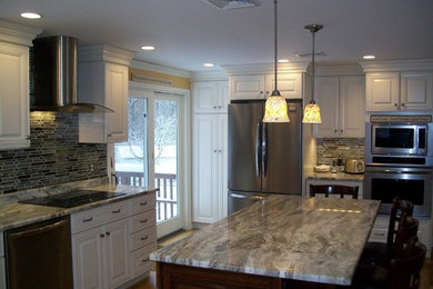 Inspiration for a mid-sized l-shaped light wood floor eat-in kitchen remodel in Wilmington with an undermount sink, raised-panel cabinets, white cabinets, granite countertops, multicolored backsplash, glass sheet backsplash, stainless steel appliances and an island