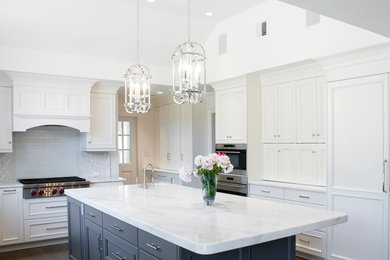 Inspiration for a mid-sized transitional dark wood floor and brown floor eat-in kitchen remodel in Other with a drop-in sink, shaker cabinets, white cabinets, marble countertops, white backsplash, ceramic backsplash, stainless steel appliances and an island