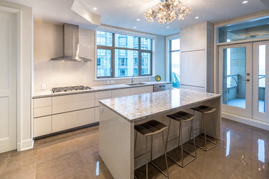 Large modern l-shaped open plan kitchen in Vancouver with a submerged sink, glass-front cabinets, white cabinets, granite worktops, white splashback, stainless steel appliances and an island.