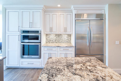 Example of a classic u-shaped porcelain tile eat-in kitchen design in Miami with white cabinets, granite countertops, gray backsplash, glass tile backsplash, stainless steel appliances and an island