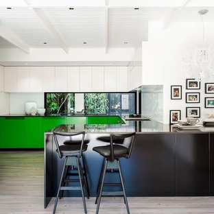 Design ideas for a contemporary u-shaped kitchen in Melbourne with flat-panel cabinets, green cabinets, window splashback, a peninsula, beige floor and black benchtop.