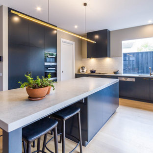 This is an example of a mid-sized contemporary kitchen in Melbourne with flat-panel cabinets, black cabinets, quartz benchtops, white splashback, porcelain splashback, black appliances, with island, beige floor, grey benchtop, a double-bowl sink and light hardwood floors.