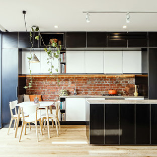 Design ideas for a contemporary eat-in kitchen in Melbourne with flat-panel cabinets, black cabinets, red splashback, brick splashback, light hardwood floors, with island and beige floor.