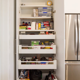 Esempio di una cucina minimalista di medie dimensioni con ante lisce, ante bianche, top in quarzo composito, paraspruzzi grigio, paraspruzzi con lastra di vetro, elettrodomestici in acciaio inossidabile, parquet chiaro e isola