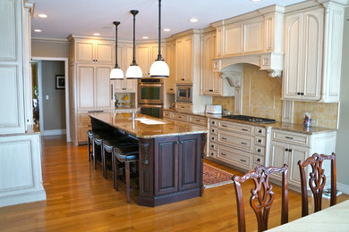 Example of a mid-sized classic l-shaped medium tone wood floor eat-in kitchen design in Chicago with a double-bowl sink, recessed-panel cabinets, white cabinets, marble countertops, beige backsplash, ceramic backsplash, stainless steel appliances and an island