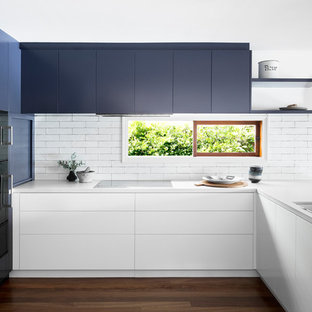 Mid-sized contemporary u-shaped eat-in kitchen in Melbourne with an undermount sink, flat-panel cabinets, blue cabinets, white splashback, black appliances, dark hardwood floors, quartz benchtops and window splashback.