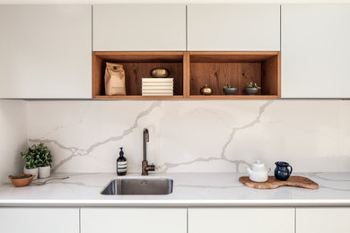 Medium sized modern l-shaped kitchen in London with a submerged sink, flat-panel cabinets, quartz worktops, white splashback, engineered quartz splashback, integrated appliances, no island and white worktops.