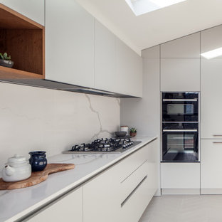 Design ideas for a medium sized modern l-shaped kitchen in London with a submerged sink, flat-panel cabinets, quartz worktops, white splashback, engineered quartz splashback, no island, white worktops, black appliances, white cabinets, grey floors and a vaulted ceiling.