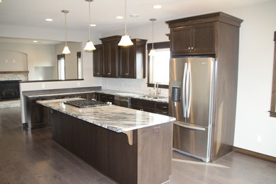Design ideas for a large contemporary l-shaped kitchen in Minneapolis with shaker cabinets, dark wood cabinets, white splashback, stainless steel appliances, dark hardwood flooring and an island.