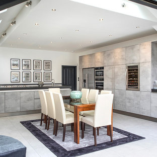 Inspiration for a large contemporary l-shaped kitchen/diner in London with flat-panel cabinets, distressed cabinets, stainless steel appliances, an island, grey floors, black worktops and granite worktops.