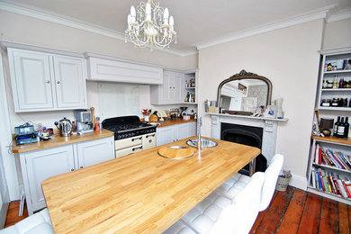 Classic kitchen in Other with grey cabinets, wood worktops, glass sheet splashback, dark hardwood flooring and an island.