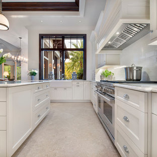 Esempio di una grande cucina tropicale con lavello stile country, ante in stile shaker, ante bianche, top in marmo, paraspruzzi bianco, paraspruzzi in lastra di pietra, elettrodomestici da incasso, pavimento in pietra calcarea, isola e pavimento beige