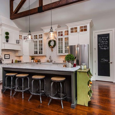 Inspiration for a timeless l-shaped kitchen remodel in Orlando with a farmhouse sink, glass-front cabinets, marble countertops, beige backsplash, subway tile backsplash, stainless steel appliances and white cabinets