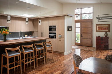 Inspiration for a contemporary u-shaped medium tone wood floor and brown floor open concept kitchen remodel in Seattle with a single-bowl sink, flat-panel cabinets, light wood cabinets, quartz countertops, glass tile backsplash, paneled appliances, an island and white countertops