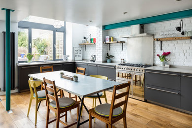 ロンドンにあるインダストリアルスタイルのおしゃれなキッチン (ダブルシンク、フラットパネル扉のキャビネット、グレーのキャビネット、コンクリートカウンター、白いキッチンパネル、レンガのキッチンパネル、シルバーの調理設備、無垢フローリング、アイランドなし) の写真