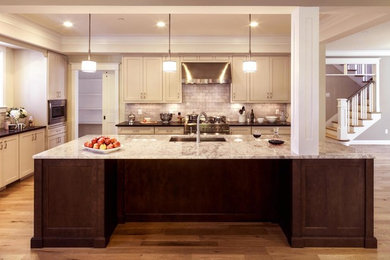 Mid-sized transitional l-shaped light wood floor open concept kitchen photo in DC Metro with an undermount sink, shaker cabinets, beige cabinets, granite countertops, gray backsplash, stone tile backsplash, stainless steel appliances and an island