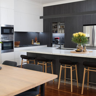 Inspiration for a contemporary l-shaped kitchen in Brisbane with an undermount sink, flat-panel cabinets, black cabinets, black splashback, mosaic tile splashback, stainless steel appliances, dark hardwood floors, with island, brown floor and white benchtop.