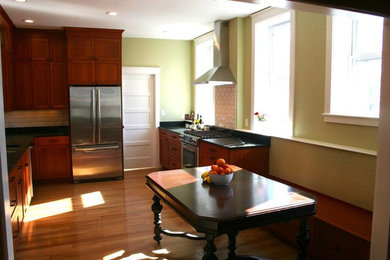 Example of a large classic u-shaped medium tone wood floor enclosed kitchen design in Boston with dark wood cabinets, white backsplash and stainless steel appliances