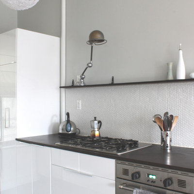 Minimalist kitchen photo in New York with flat-panel cabinets and white backsplash