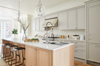 Mid-sized transitional l-shaped medium tone wood floor and beige floor open concept kitchen photo in New York with an undermount sink, gray cabinets, quartz countertops, white backsplash, marble backsplash, paneled appliances, an island, white countertops and recessed-panel cabinets