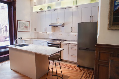 Eat-in kitchen - large transitional l-shaped medium tone wood floor eat-in kitchen idea in New York with an undermount sink, flat-panel cabinets, white cabinets, granite countertops, white backsplash, ceramic backsplash, stainless steel appliances and an island